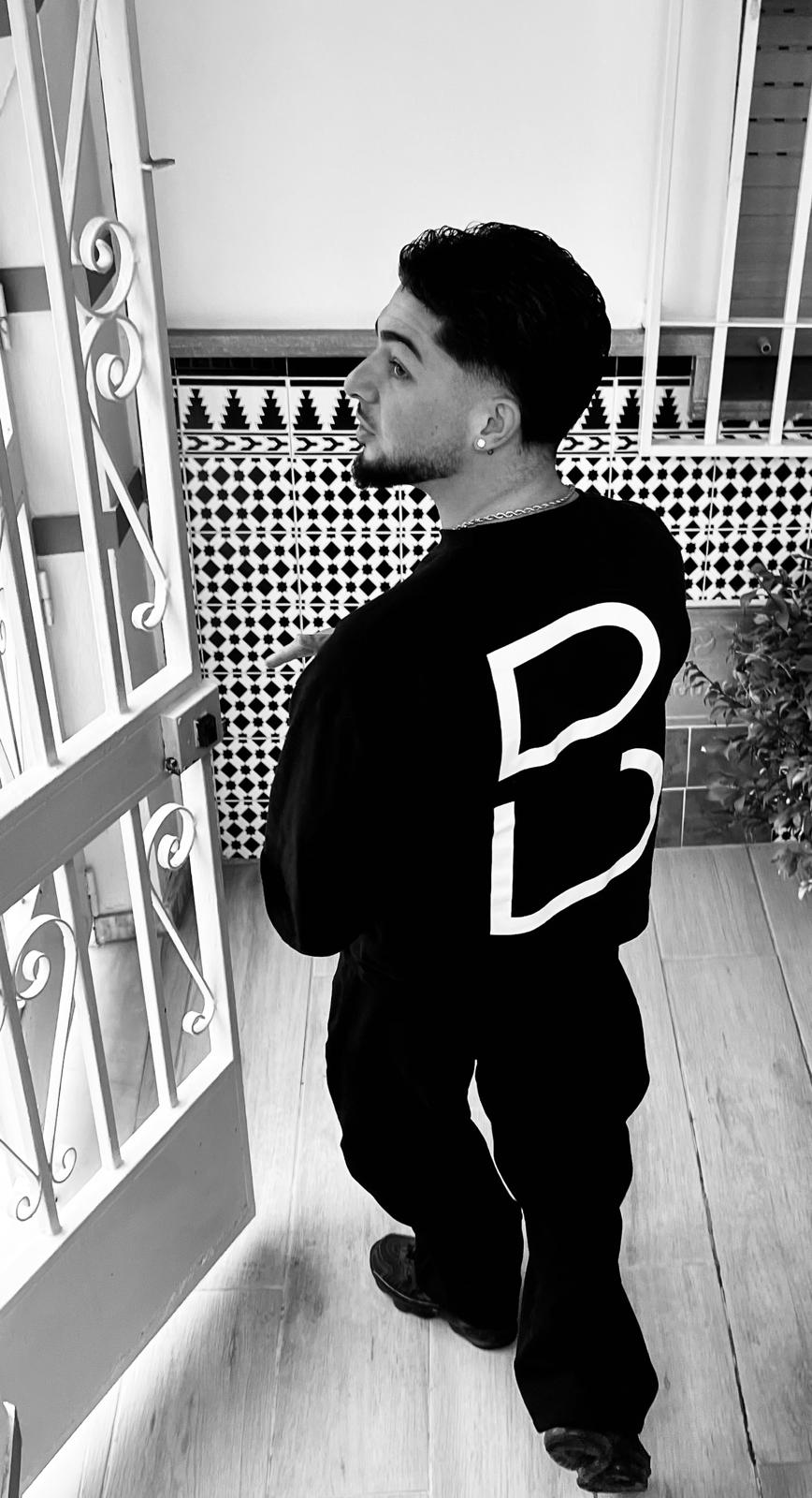 Retrato en blanco y negro de una persona de pie junto a una puerta abierta.